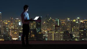 HSBC image of a man in a room overlooking a city at night, laptop in hand