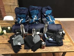 An assortment of warm, winter clothes, sleeping bags and backpacks on a table