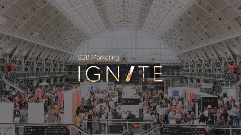 Ignite 2018 logo with conference hall full of people as the background